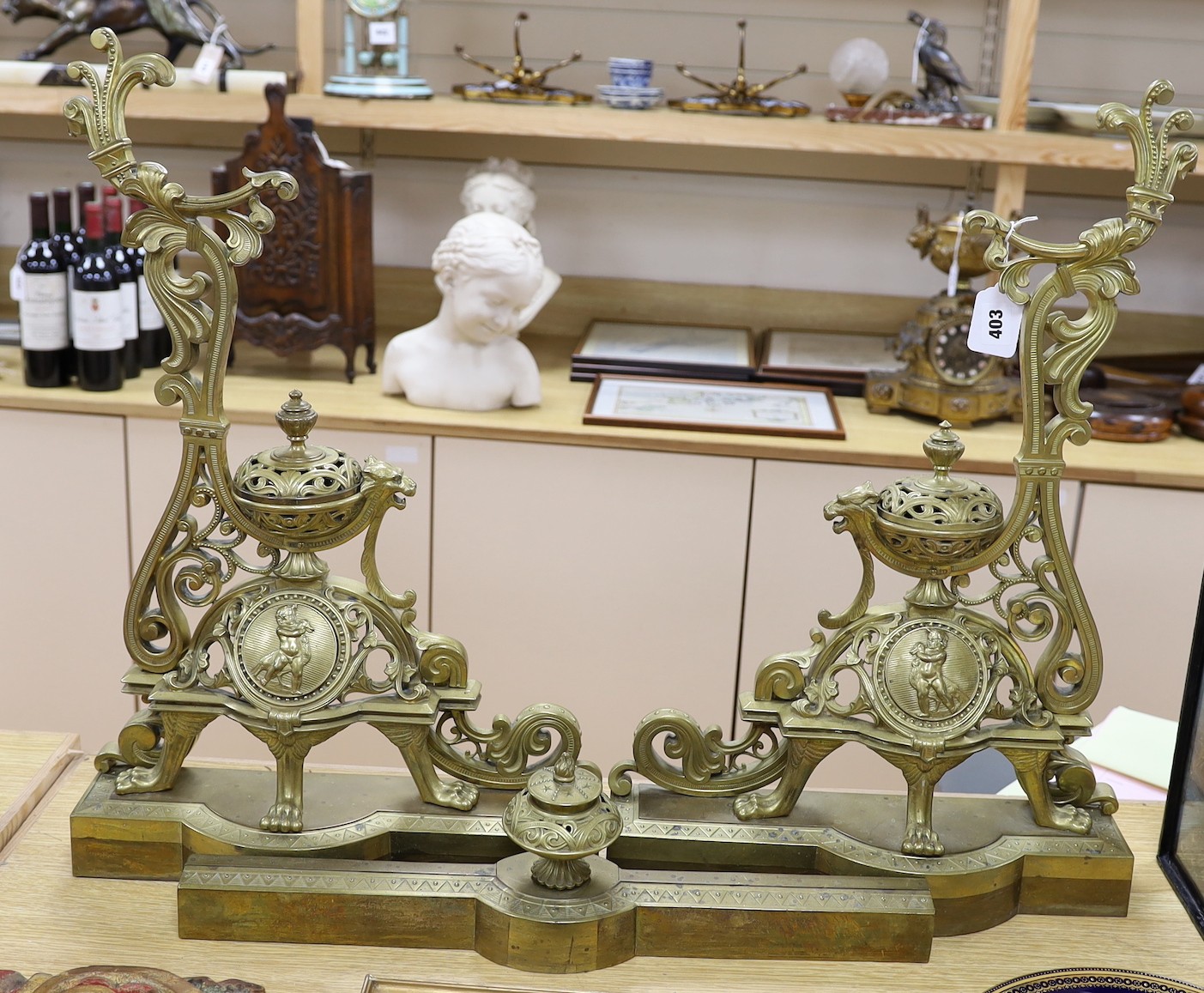 A pair of French bronze chenets, 19th century, with ornate decoration and cherub cartouche, adjustable curb, 64 cms high